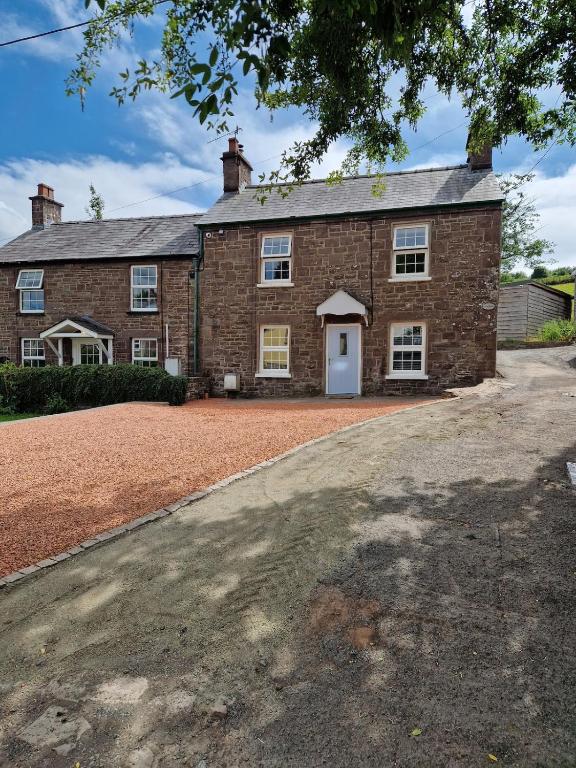 an old brick house with a white door at Pentwyn Cottage, Bwlch Brecon in Bwlch