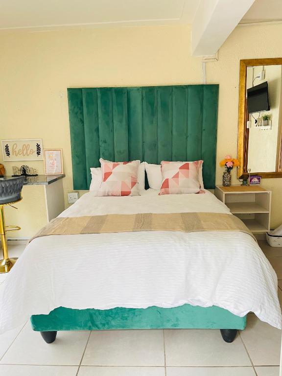 a bedroom with a large bed with a green headboard at Harmony Spaces in Kempton Park