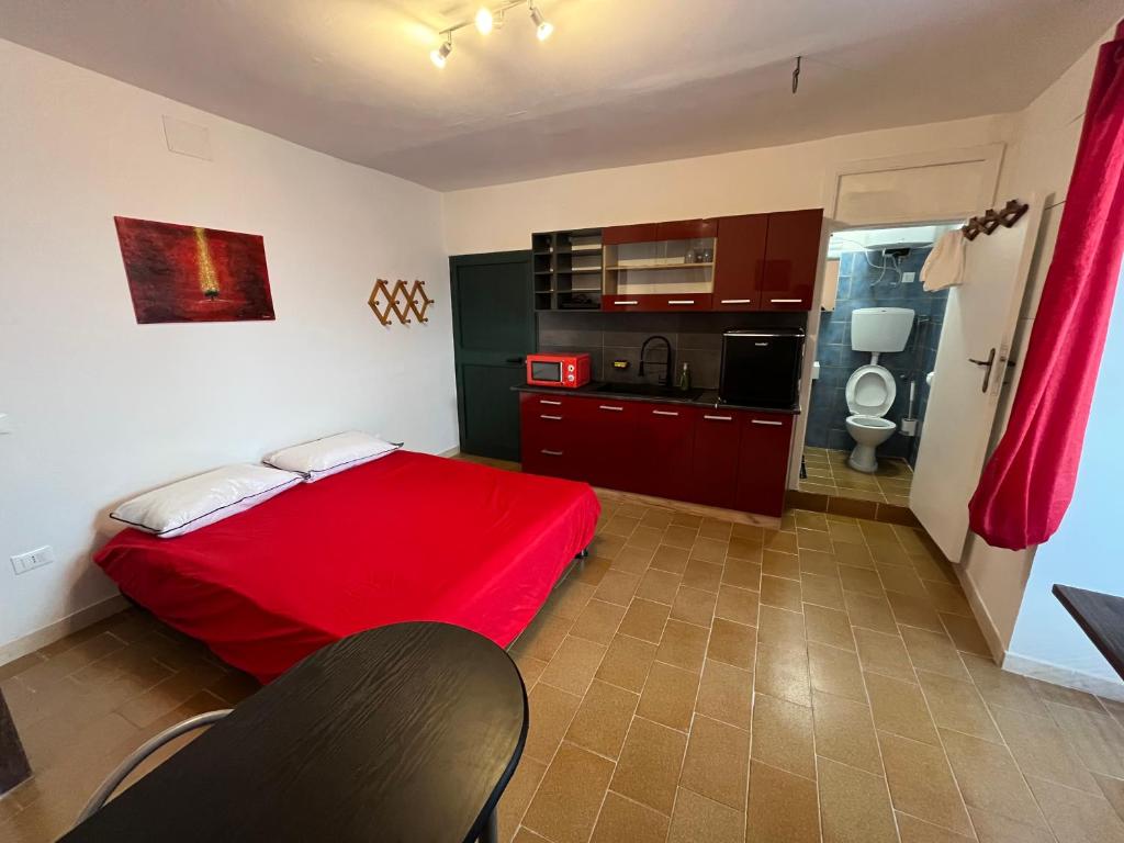 a bedroom with a red bed and a kitchen at La casetta in Lettomanoppello