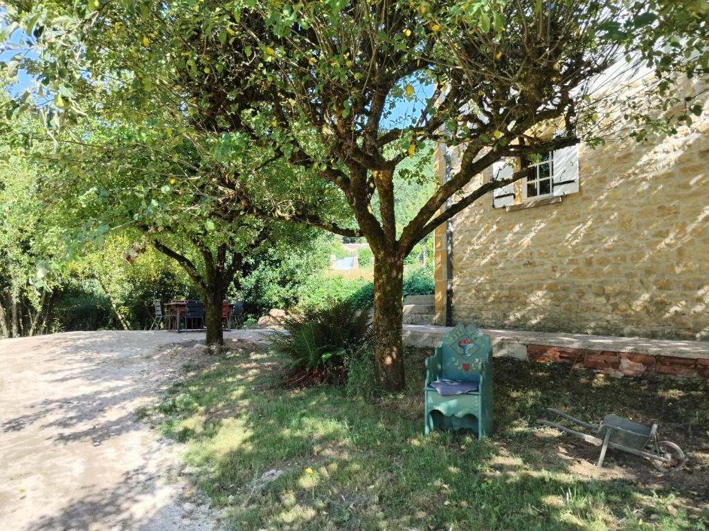 une chaise bleue assise sous un arbre à côté d'un bâtiment dans l'établissement Maison au bord d'un cours d'eau, à Castels
