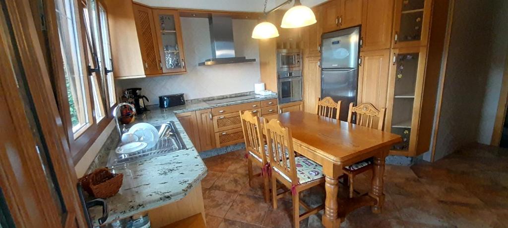 una cucina con tavolo in legno e sedie in legno di EnSAN CIPRIAN Casa Mirando al Mar a Cervo