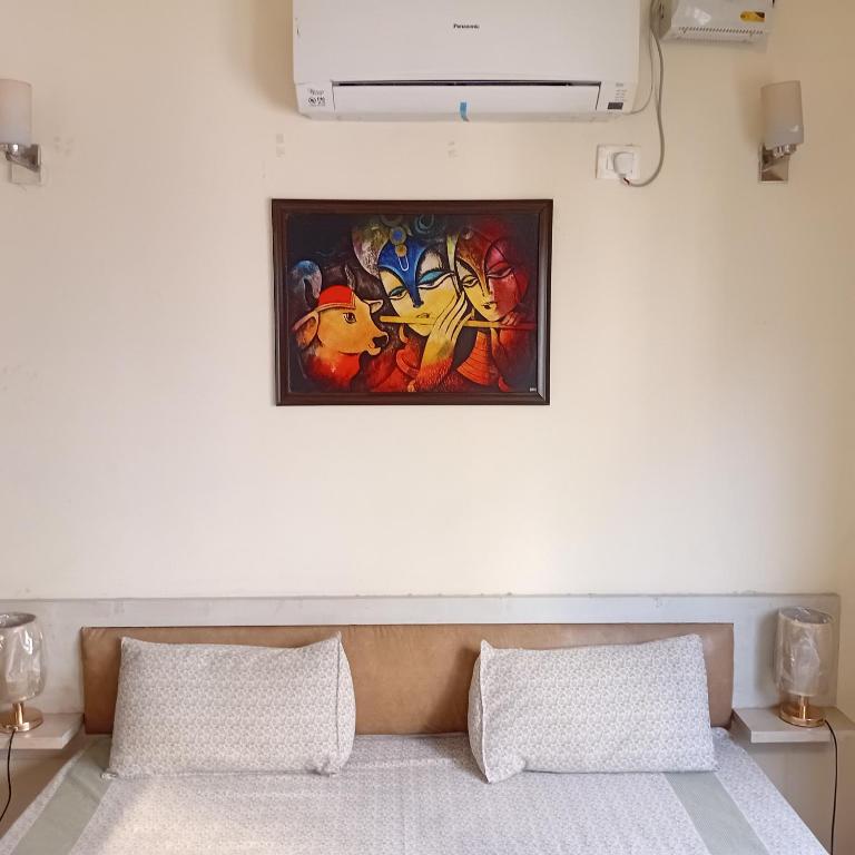 ein Gemälde an einer Wand über einem Bett mit zwei Kissen in der Unterkunft Organic Stay in Greater Noida
