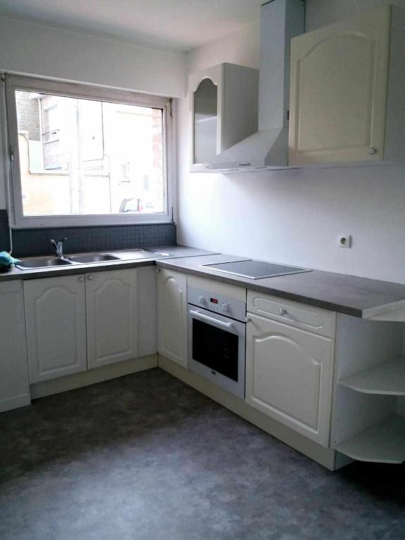 une cuisine avec des armoires blanches, un évier et une fenêtre dans l'établissement Malo-les-Bains Appartement 1 chambre, à Dunkerque