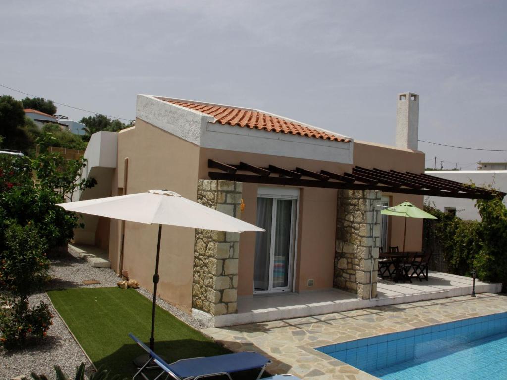 a house with an umbrella and a swimming pool at Pretty Holiday Home in Grays in Loutra