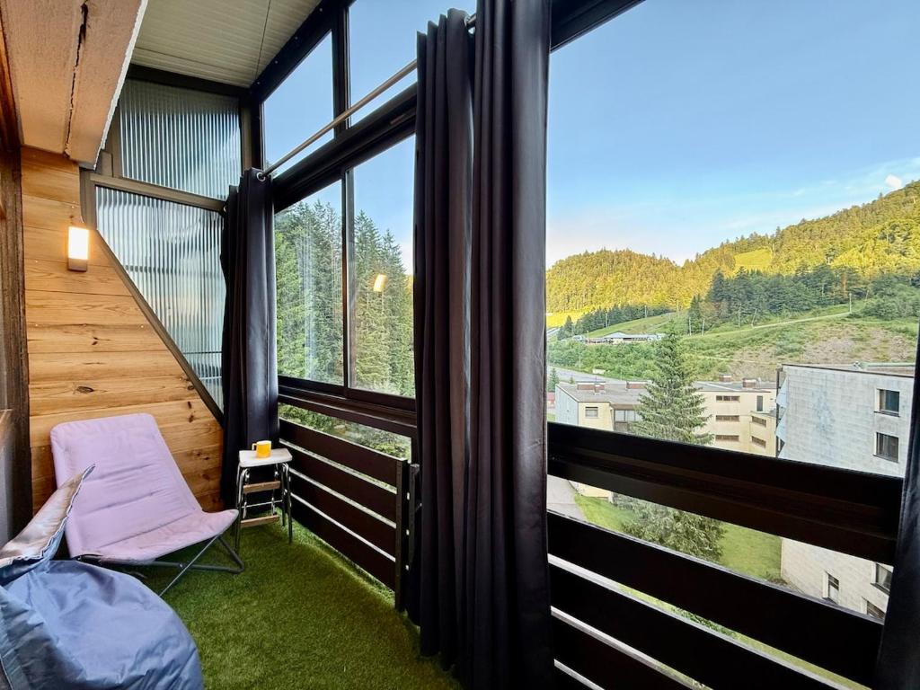 un balcon avec une chaise et une grande fenêtre dans l'établissement Appart 313, au pied des pistes de ski avec superbe vue, à La Bresse