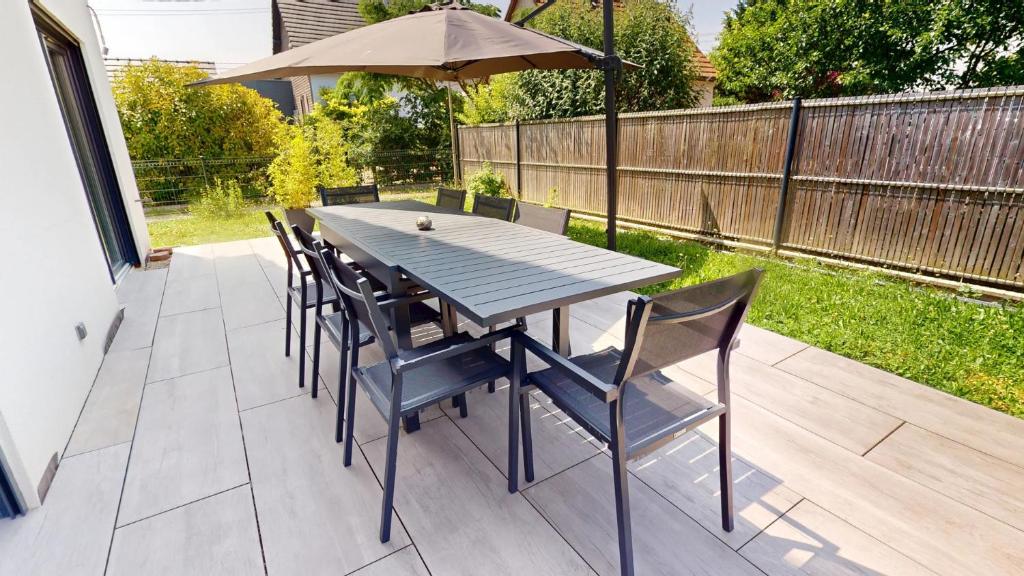 - une table en bois avec des chaises et un parasol sur la terrasse dans l'établissement Maison spacieuse et moderne Strasbourg, à Ostwald