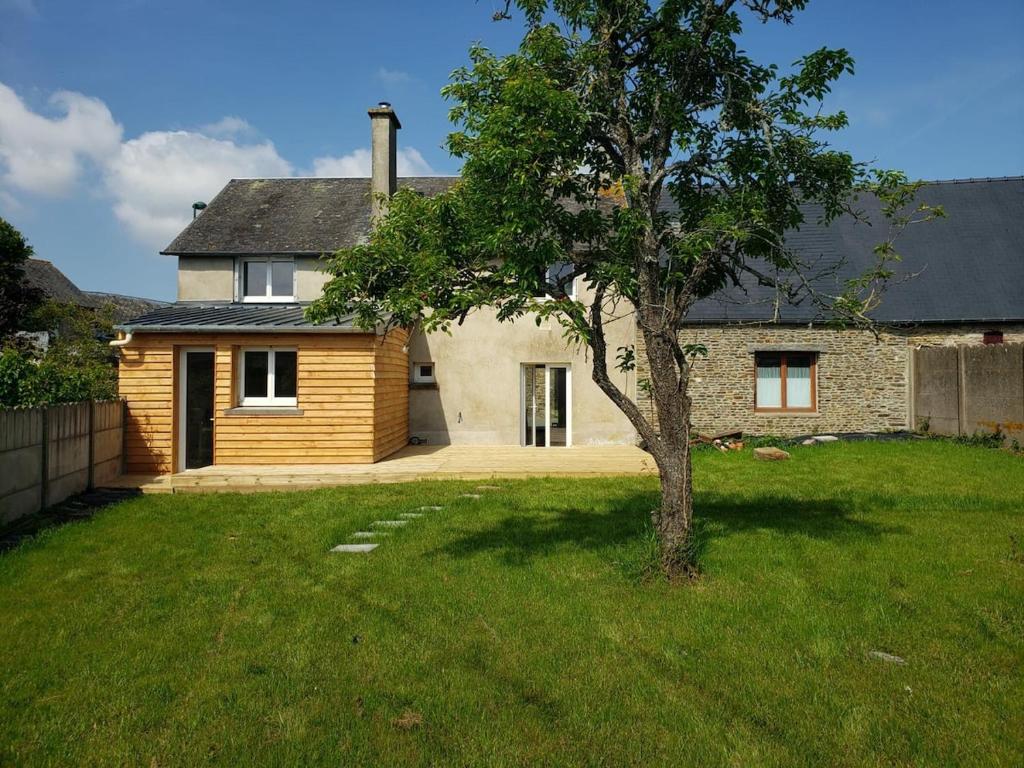 une maison avec un arbre dans la cour dans l'établissement Les Darons du Mont-Saint-Michel 14 people, à Pontorson