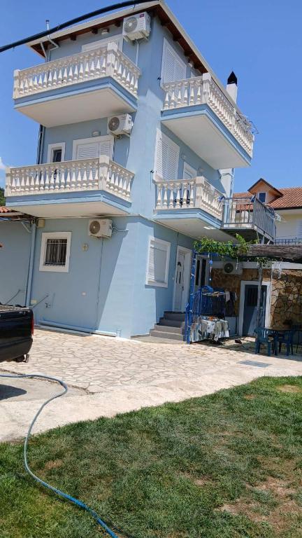 a blue house with white balconies and a yard at ChristAlex Guesthouse in Himare
