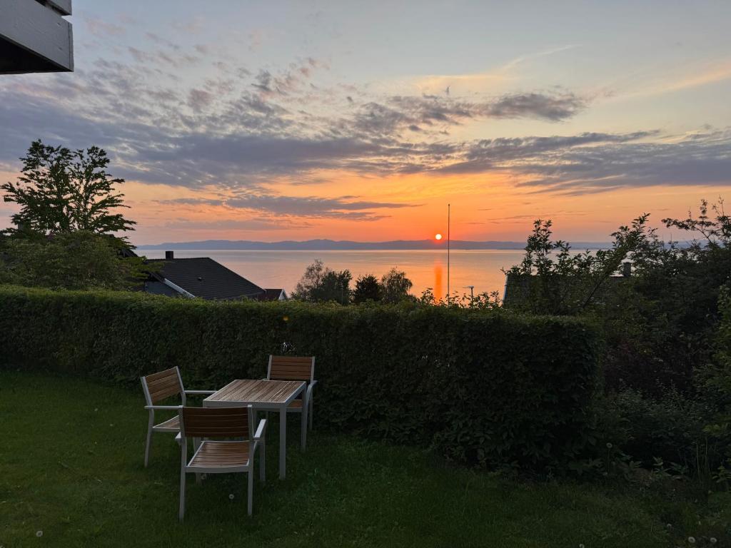 a table and chairs with the sunset in the background at Appartment with garden and a big bathroom in Malvik