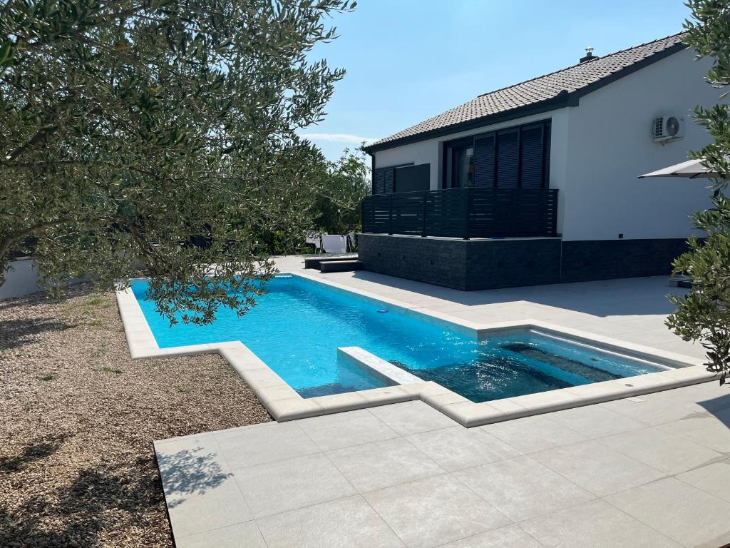 a swimming pool in a yard next to a house at Kuća za odmor Laura in Biograd na Moru
