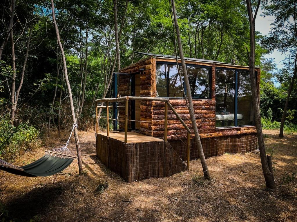 a tree house with a hammock in the woods at Insolite Le Coin du Bûcheron in Monts-sur-Guesnes
