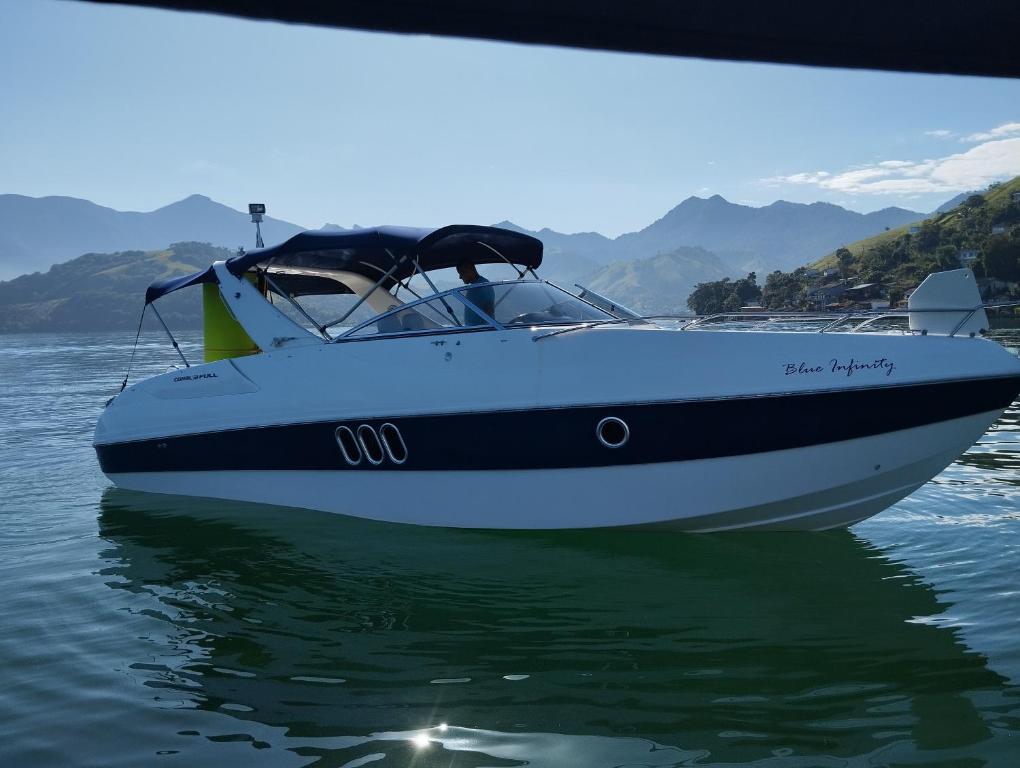 a white boat sitting in the water at Suite pé na areia - trilha e praia in Angra dos Reis