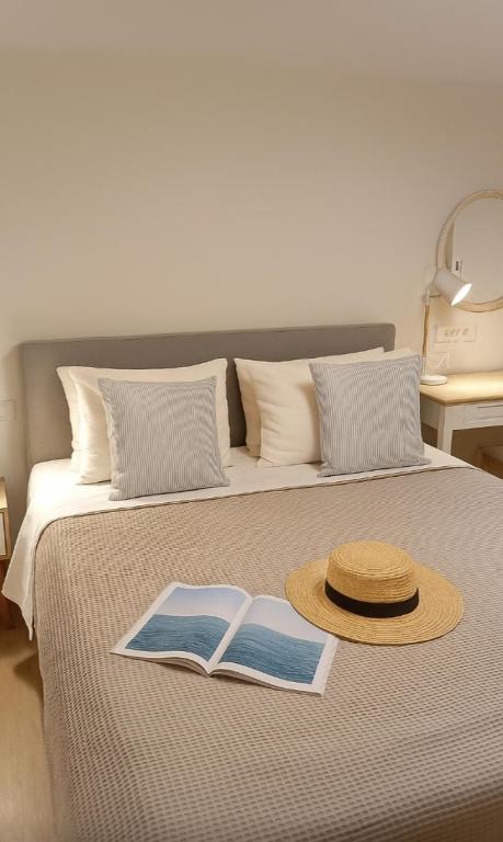 un sombrero de paja y un libro en una cama en Thalassa loft in Tolo, en Tolo