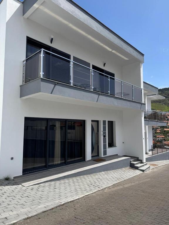 a white house with a balcony on top of it at Beautiful Modern Townhouse with Parking Included in Machico