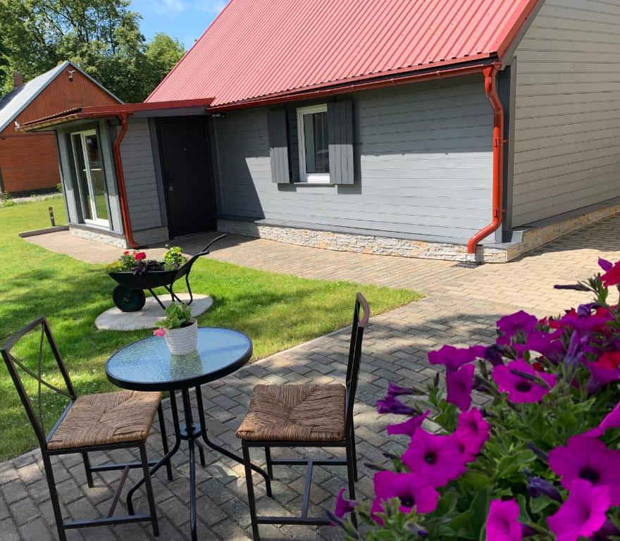 a patio with a table and chairs and purple flowers at Guest House in Ventspils