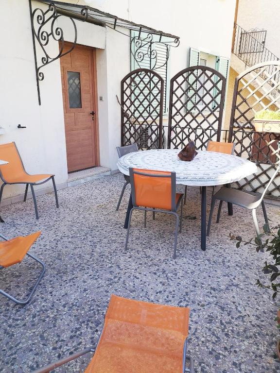 a patio with a table and chairs and a door at Le cœur de saint Florent in Saint-Florent