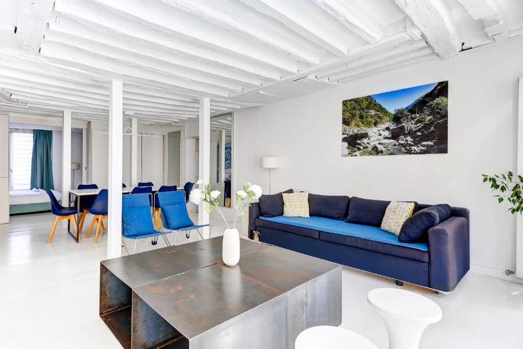 un salon avec un canapé bleu et une table dans l'établissement Appartement Rue Montorgueil Calme et Design, à Paris