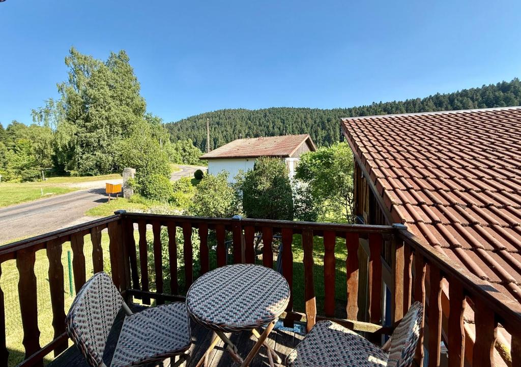 - un balcon avec deux chaises, une table et une maison dans l'établissement Le Cresson, charmant et spacieux avec balcon, à Gérardmer