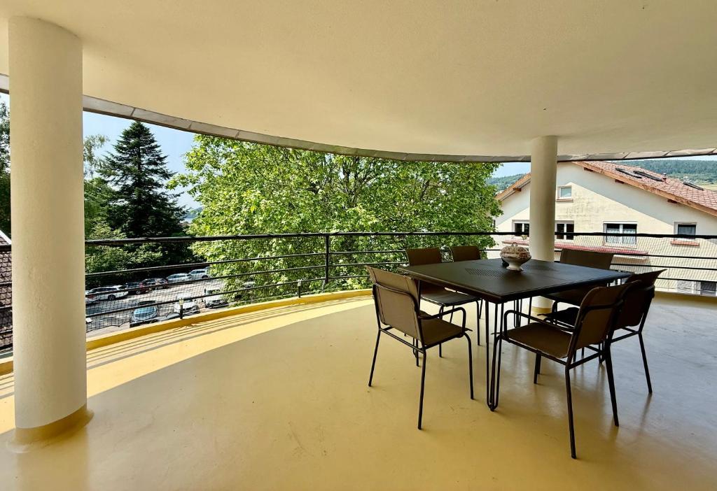 une table noire et des chaises sur un balcon dans l'établissement La Tour du Lac, gîte bel & spacieux à côté du lac de Gerardmer, à Gérardmer