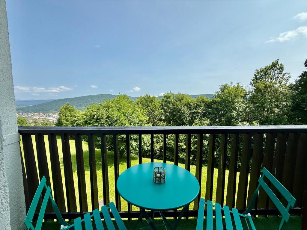 une table bleue et deux chaises sur un balcon dans l'établissement Les Xettes, bel appartement style chalet & balcon, à Gérardmer