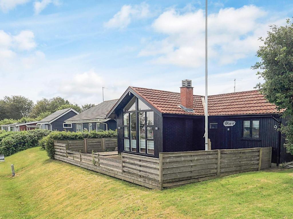 a black house with a wooden fence in a yard at 4 person holiday home in Sæby-By Traum in Sæby