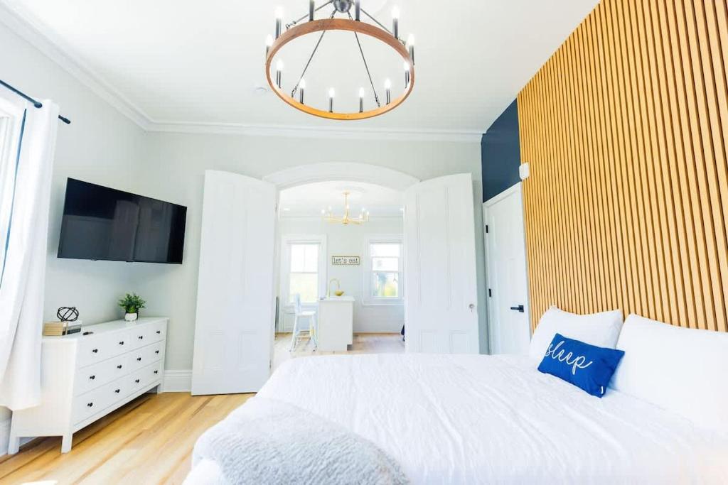 a bedroom with a white bed and a chandelier at Jennifer's Spa-Like Modern & Chic Broadway Retreat in Providence