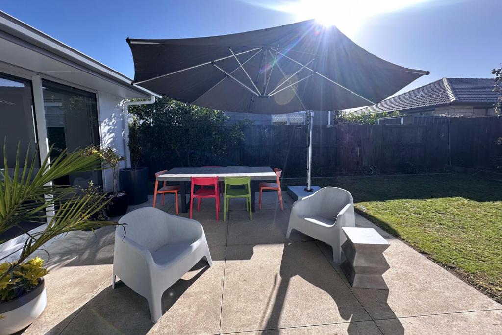 a patio with a table and chairs and an umbrella at Easy Beach Holiday in Mount Maunganui