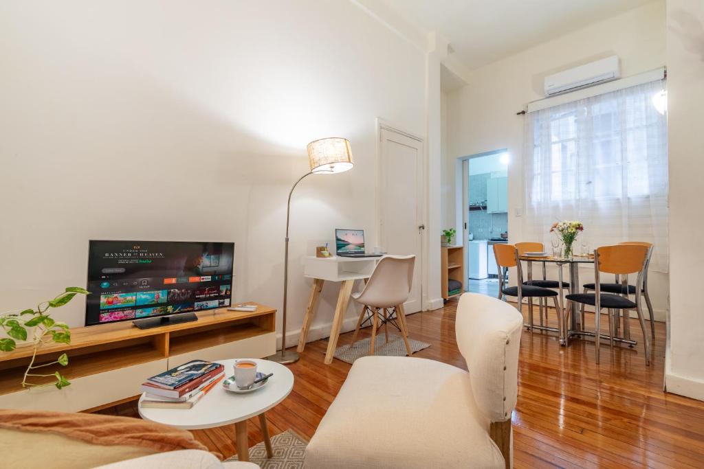 a living room with a tv and a table and chairs at Explora BA, depto céntrico junto al Obelisco con espacio de trabajo in Buenos Aires