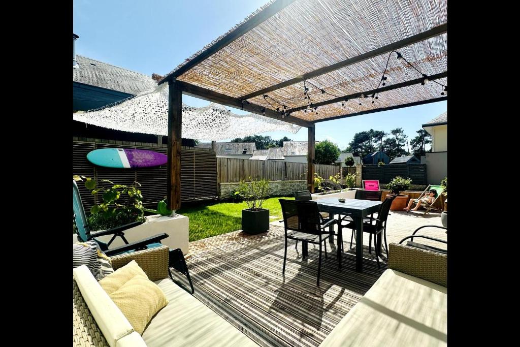 un patio avec une table et des chaises sous une pergola dans l'établissement Maison Ty Cosy, calme & plage à 10 min, à Ploemel