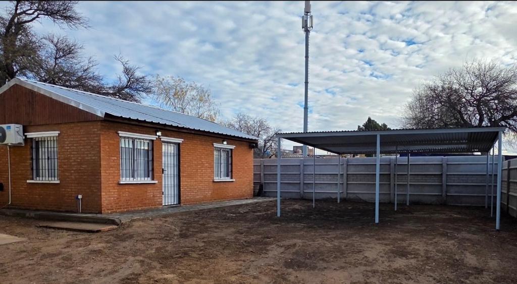 a small brick building with a fence next to it at Departamentos Los Abuelos in General Acha