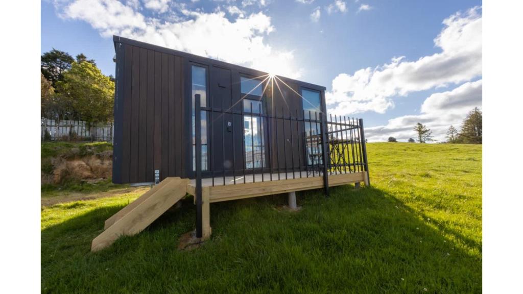 a tiny house with a deck on a field at Aorangi Peak Cabins 4 by Tiny Away in Rotorua