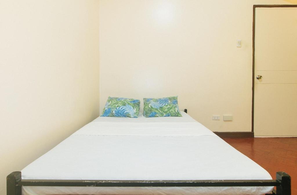 a small bedroom with a bed with white sheets and blue pillows at Winland JY7 Cebu by RedDoorz in Cebu City