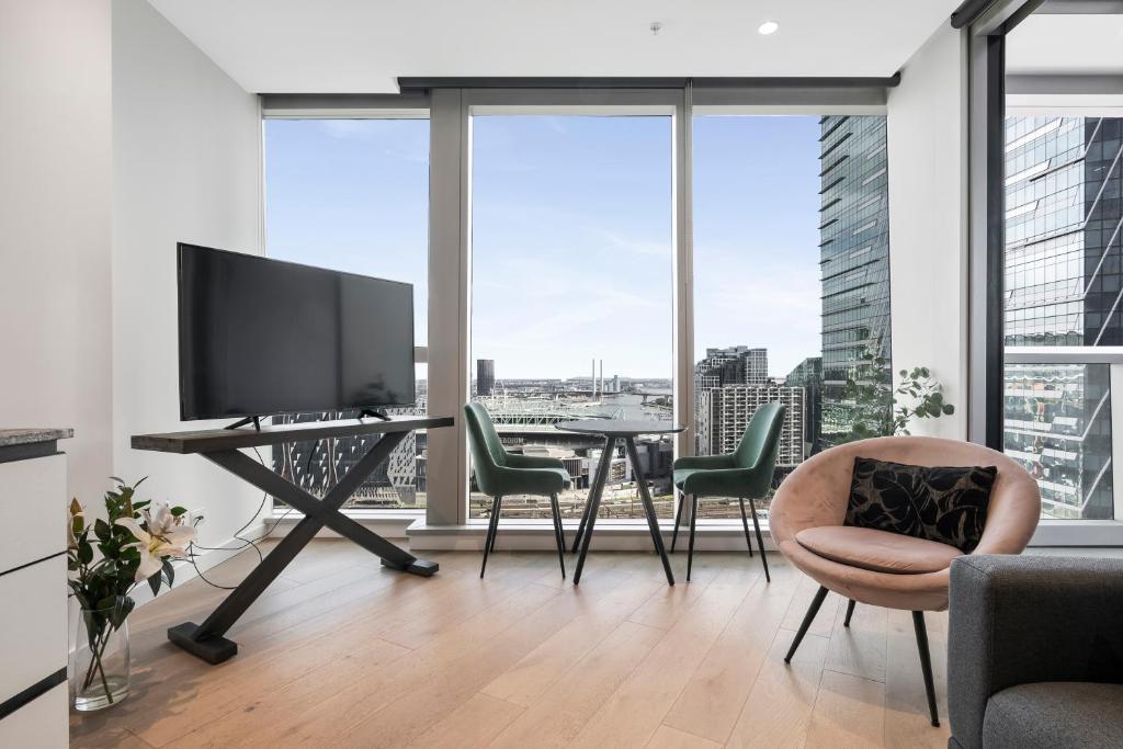 ein Wohnzimmer mit Fernseher und Tisch mit Stühlen in der Unterkunft West Side Spencer St Apt w Marvel Stadium View in Melbourne