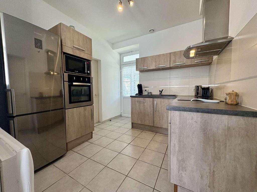 a large kitchen with stainless steel appliances and tile floors at Maison calme Saint-Denis d'Oléron proche centre et plage - FR-1-246A-364 in Saint-Denis-dʼOléron