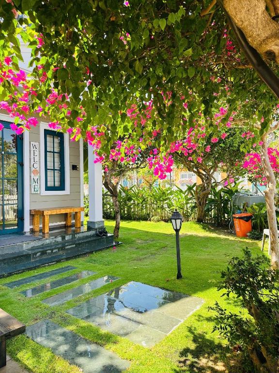a house with a garden with pink flowers at AnnA Villa Novaworld Phan Thiết in Bình Tú