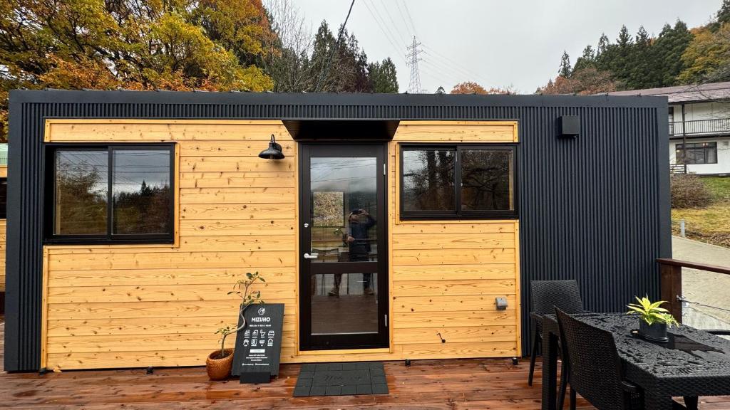 飯山市にあるTiny Homes & Sauna MIZUHOのパティオにある小さな黒と黄色の小さな家