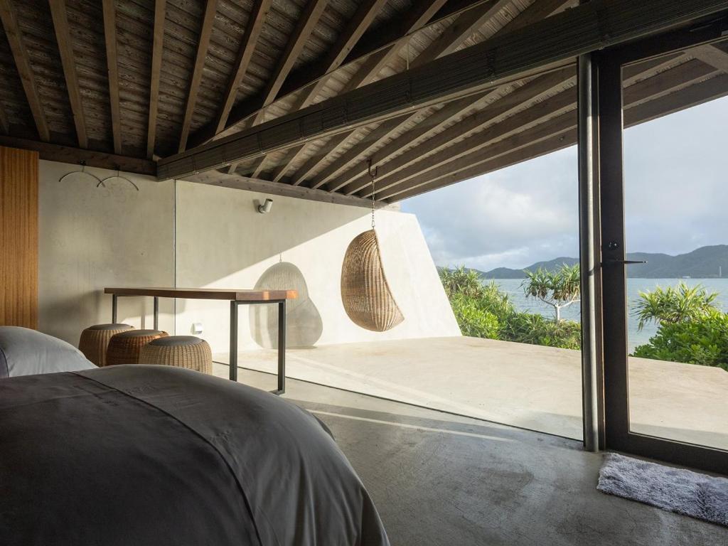a bedroom with a view of the ocean from a house at Denpaku The Beachfront MIJORA in Amami