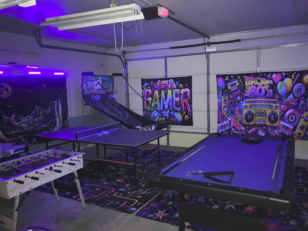 a room with ping pong tables and purple lights at Tiki Boho Pool Spa Arcade Mini Golf BBQ in Indio