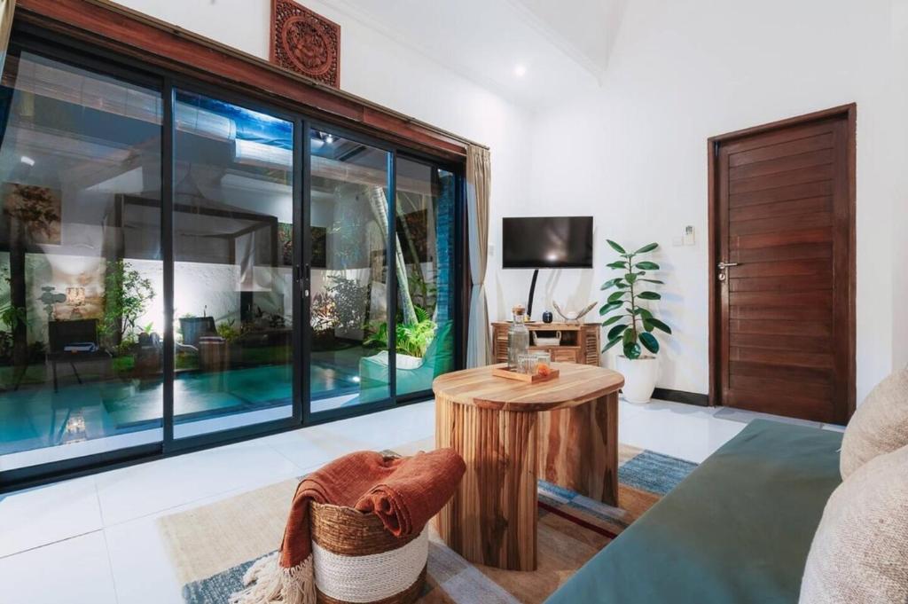 a living room with a table and a large window at Villa Chintana Sanur - Tropical lush landscapes, and serene atmospheres in Sanur