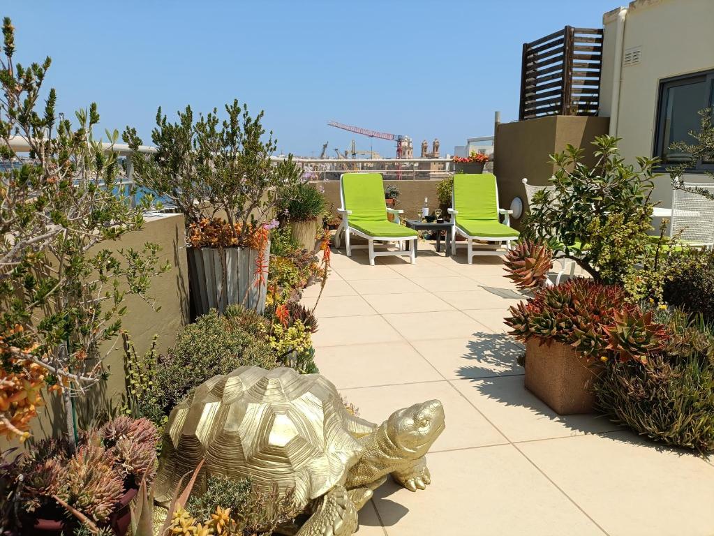 a patio with green chairs and a turtle statue at Three Cities Apartments in Cospicua