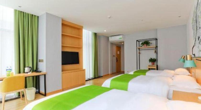 ein Schlafzimmer mit zwei Betten und einem Flachbildfernseher in der Unterkunft Vatica Hotel Hefei Yaohai Longgang Subway Station in Hefei