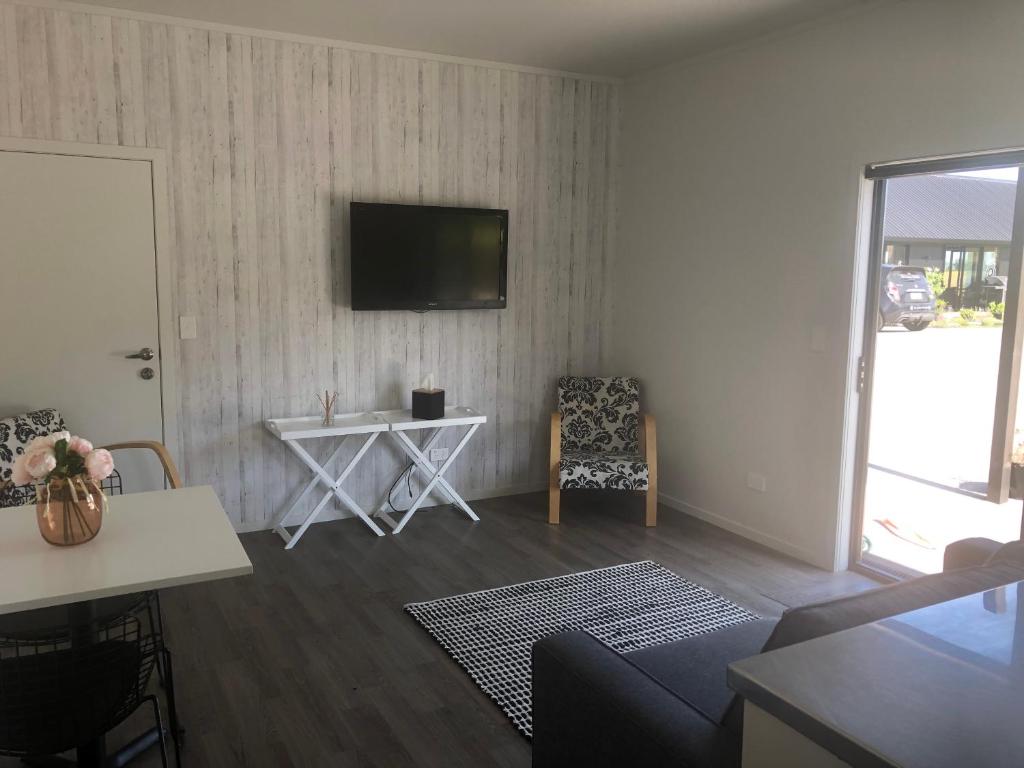 a living room with a couch and a table and a television at Night Winds Homestay in Ohaupo