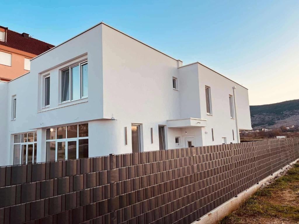 a white house behind a fence at Apartmani Leon in Međugorje
