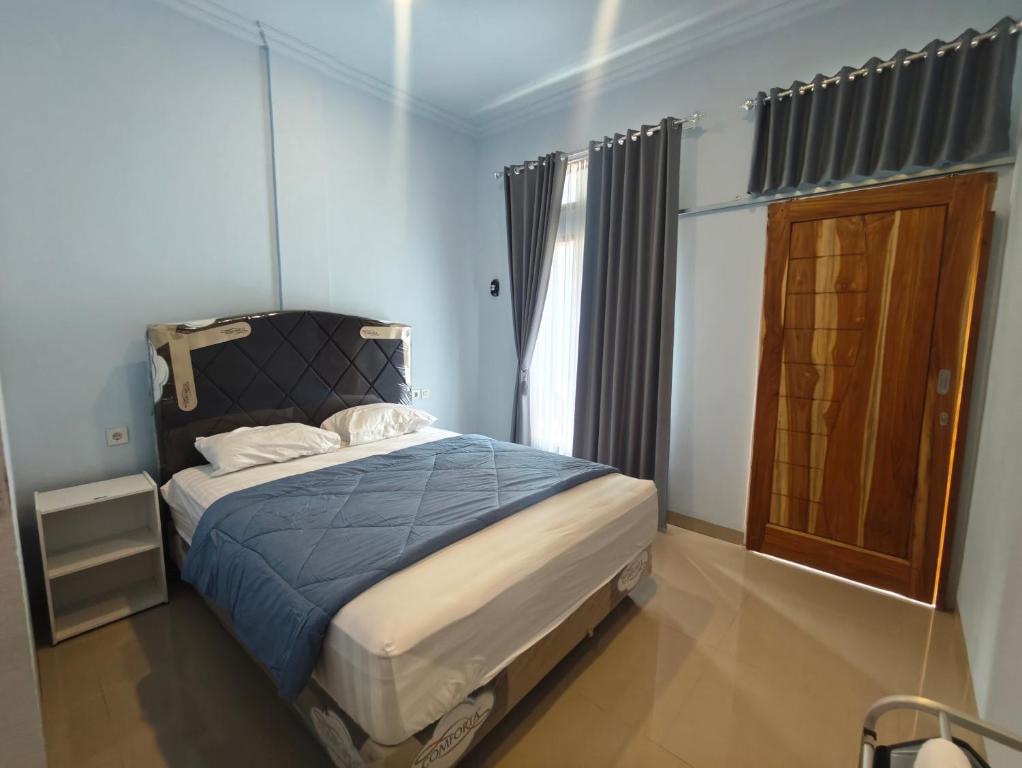 Un dormitorio con una cama con sábanas azules y una ventana. en Cherry Homestay, en Kuta Lombok