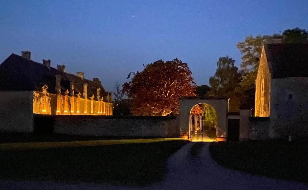 un bâtiment éclairé la nuit avec une arche dans l'établissement Le château de Grisy -13p et sa Ferme -9p, Piscine, à Vendeuvre