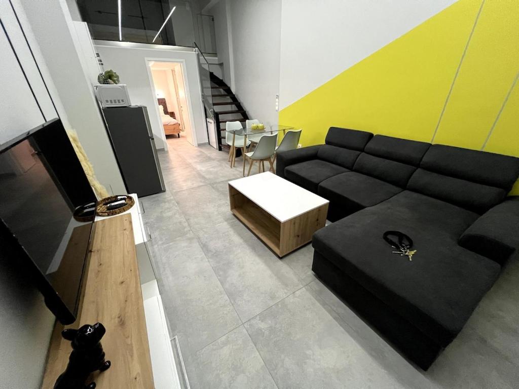 Una sala de estar con un sofá negro y una mesa. en Mandouki Urban Stay, en Corfú