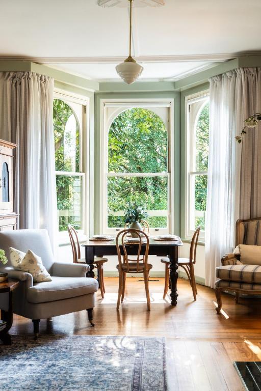 a living room with a table and chairs and windows at Woolrich Historic Garden Cottage in Olinda