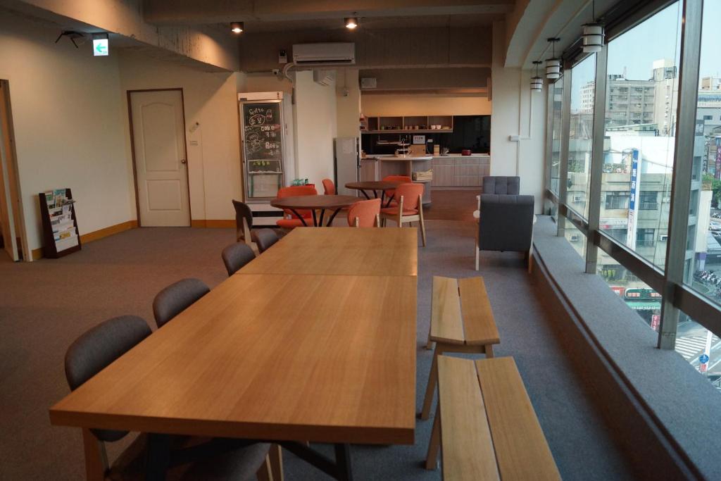 a cafeteria with wooden tables and chairs and windows at Trip GG Hostel in Kaohsiung