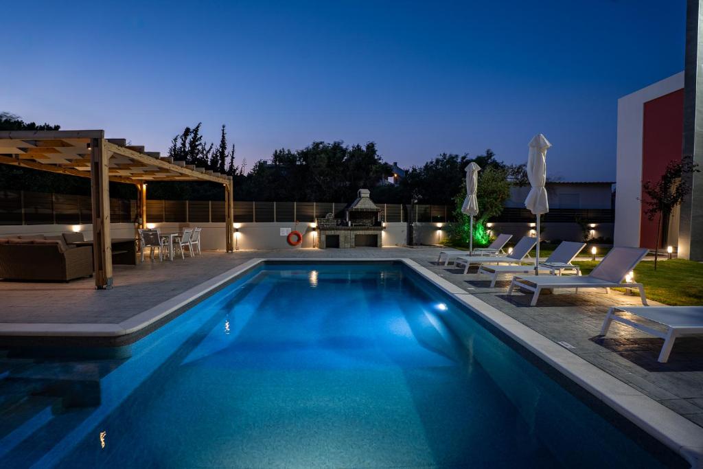 Una piscina en un patio trasero por la noche. en Villa Pasadra, en Afantou