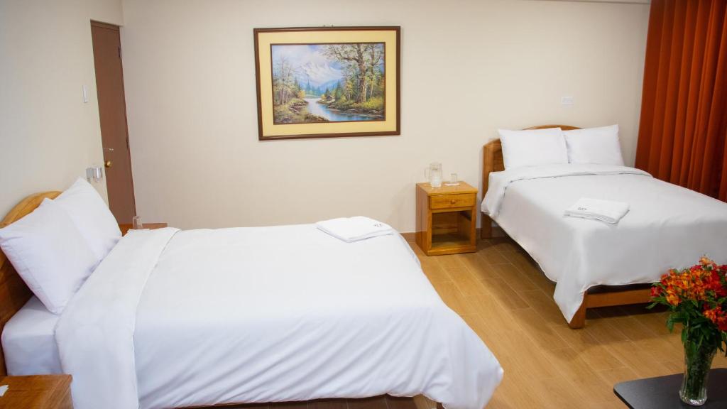 Una habitación de hotel con dos camas y un cuadro en la pared. en Hotel Centro Huancayo, en San Antonio